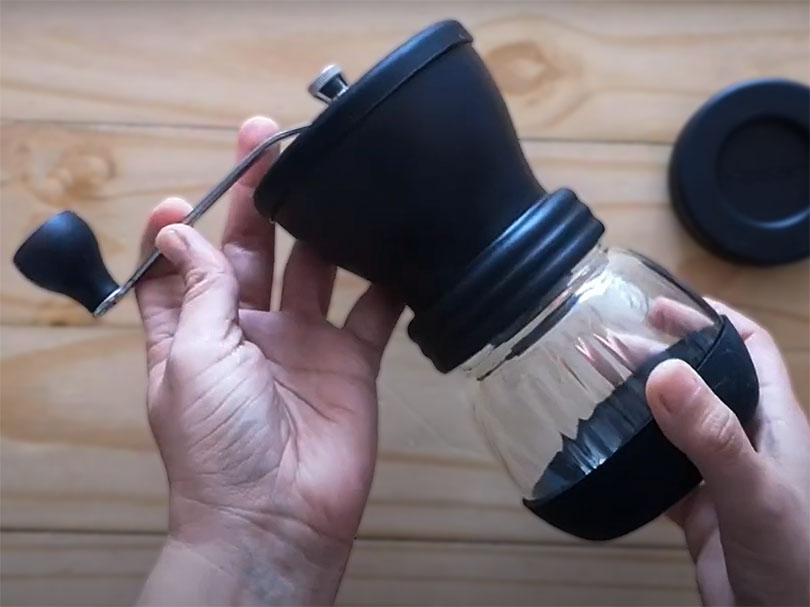 Hands holding the Hario Skerton Plus manual coffee grinder