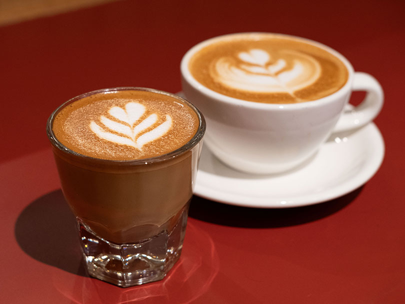 Cortado and Flat White side-by-side on red table