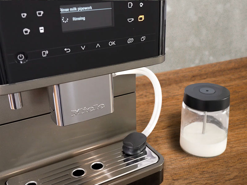 The two-tubed milk system rinsing into the Miele CM 6360's drip tray, the milk carafe is off to the side